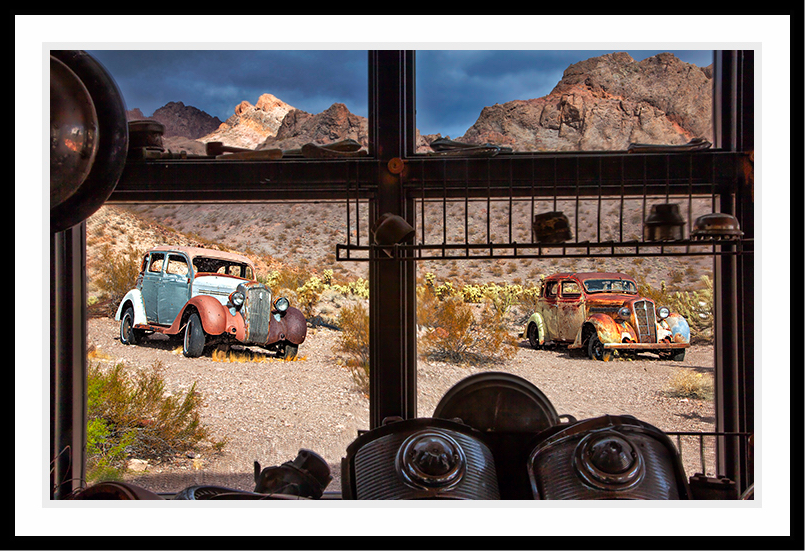 Looking through a window at old cars in the desert.